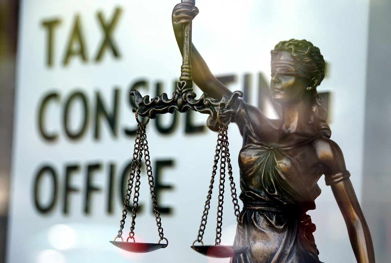 Statue der Justitia mit Waage vor verschwommenem Hintergrund mit der Aufschrift Tax Consulting Office