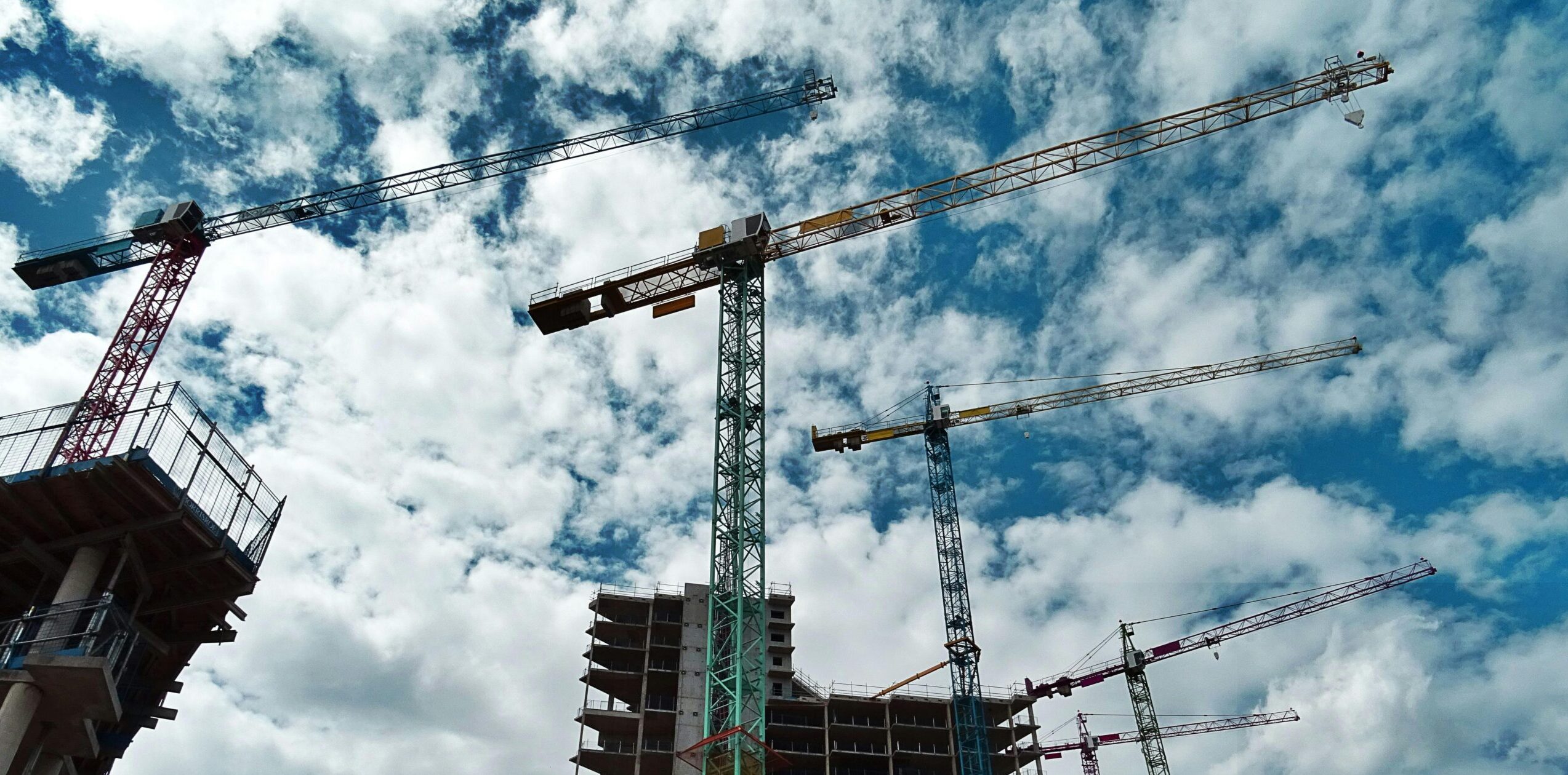 Kräne stehen vor einem Neubau. Hochhäuser werden gebaut.