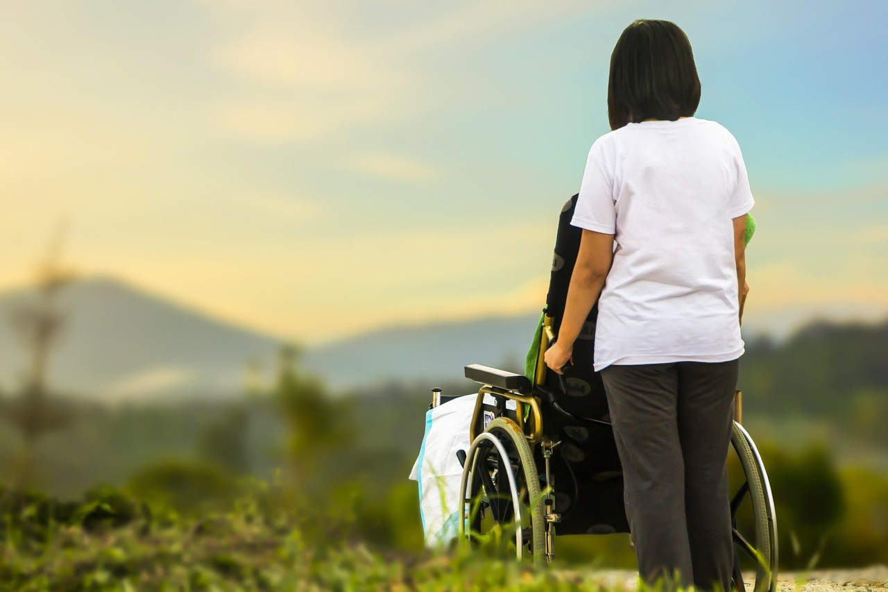 Pflegebedürftige Person im Rollstuhl mit Betreuungsperson – private Pflegeversicherung und steuerliche Vorsorge im Alter