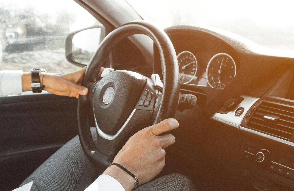 Geschäftsmann am Steuer eines Firmenwagens während der Fahrt bei Sonnenlicht.